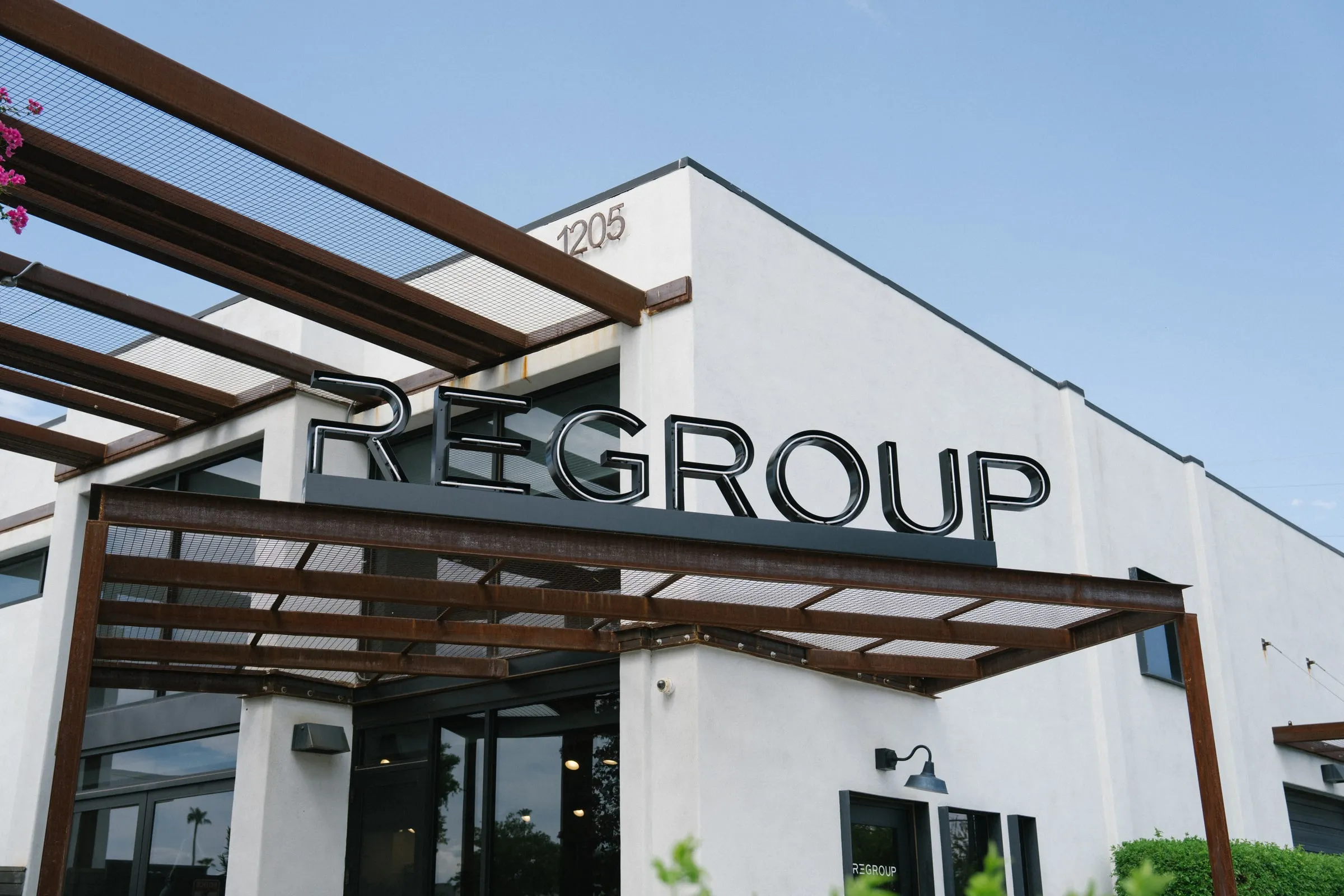 The Regroup Coffee + Bicycles building in Tempe, Arizona, with its steel canopy and sign.